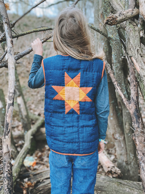 Ein Junge mit gequilteter Weste steht mit dem Rücken zum Foto. Der Rückteil der Weste ist durch einen gequilteten Stern gezeichnet.