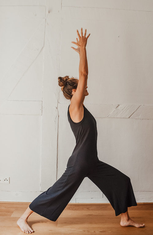Jenne steht im selbstgenähten Jumpsuit vor einer Wand und macht Yoga.